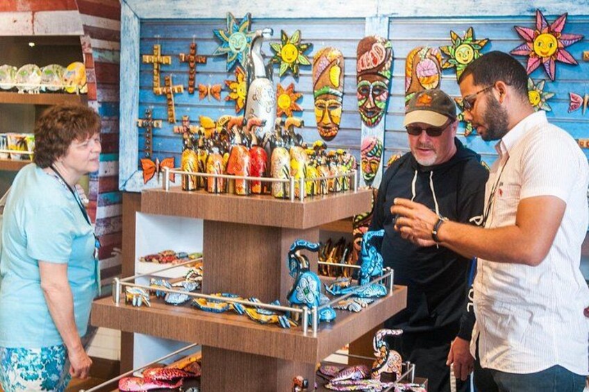 A person examining items on a wooden display stand in a store with colorful masks and decorative objects. 3