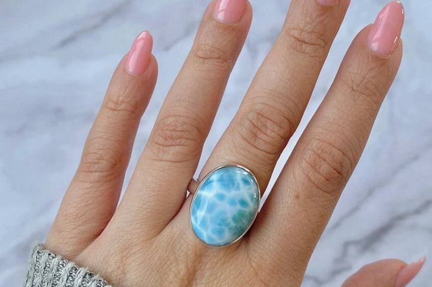 A hand with pink nail polish wearing a large turquoise ring. 2
