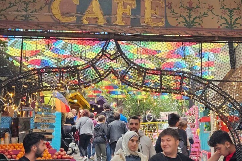 Un mercado concurrido con sombrillas de colores y un letrero que dice 'CAFE'. 2