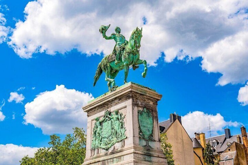 A bronze equestrian statue on a pedestal with a clear blue sky and clouds in the background. 3