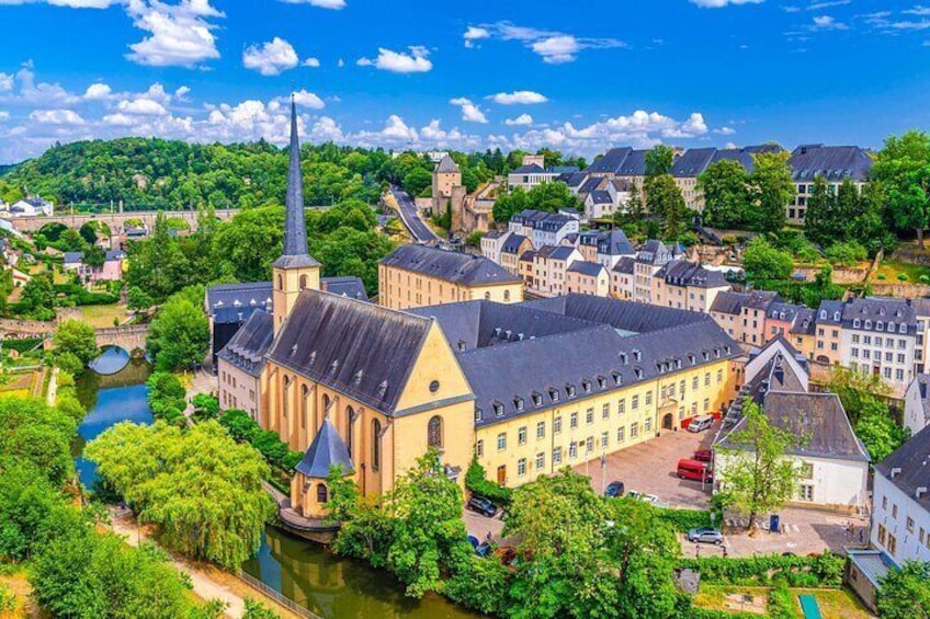 A historic town with a prominent church, a river, and surrounding greenery. 1