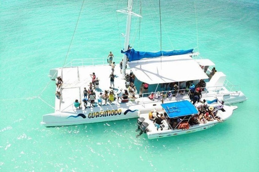 A white boat with 'GUASIMO' written on the side, floating on turquoise water. 4