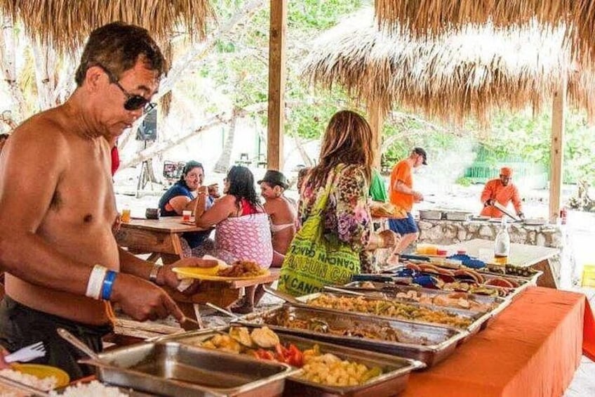 A buffet with various food items, people dining, and a thatched roof structure. 5