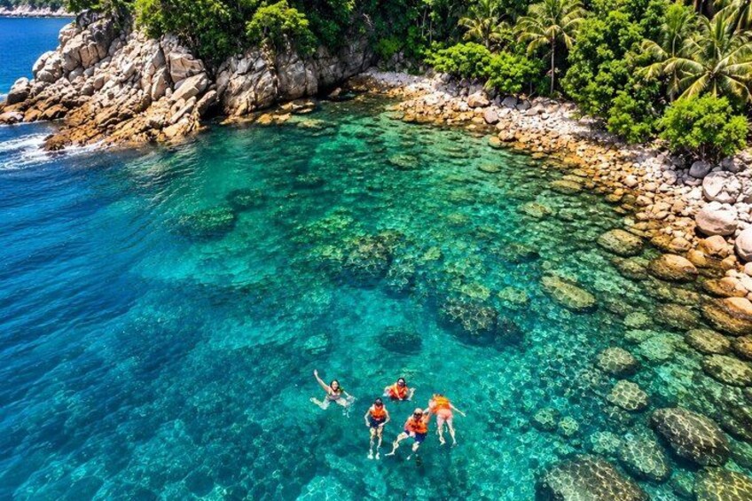 A clear turquoise sea with visible rocks and a rocky shoreline. 1