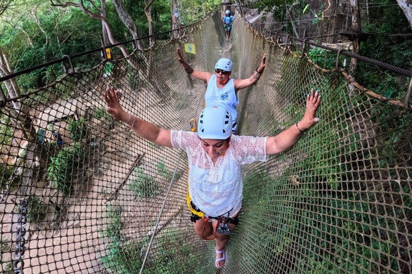 A person on a zip line with outstretched arms, wearing a helmet and a white shirt. 3