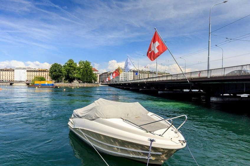 Un bateau est amarré près d’un pont, un drapeau flotte, l’eau est calme et on aperçoit des bâtiments au loin. 3