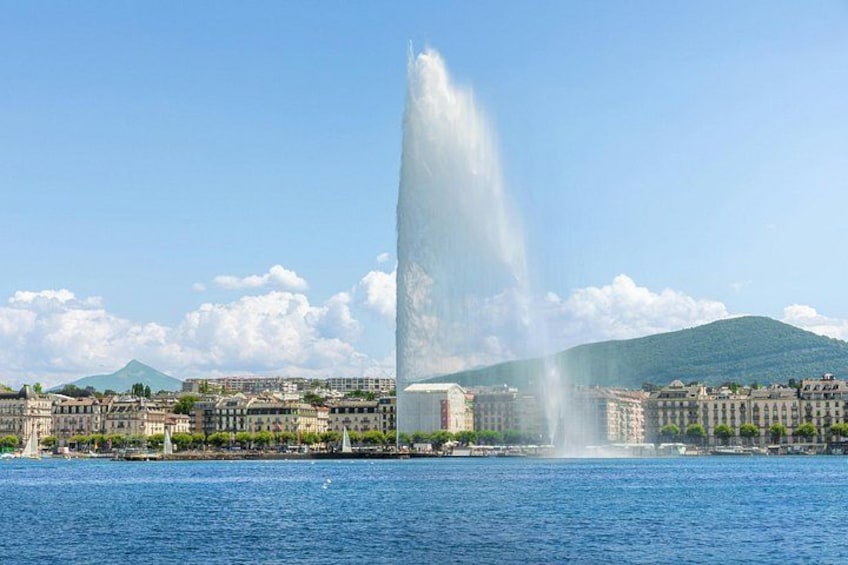 Une fontaine projetant de l’eau en l’air, une étendue d’eau et des bâtiments en arrière-plan. 2