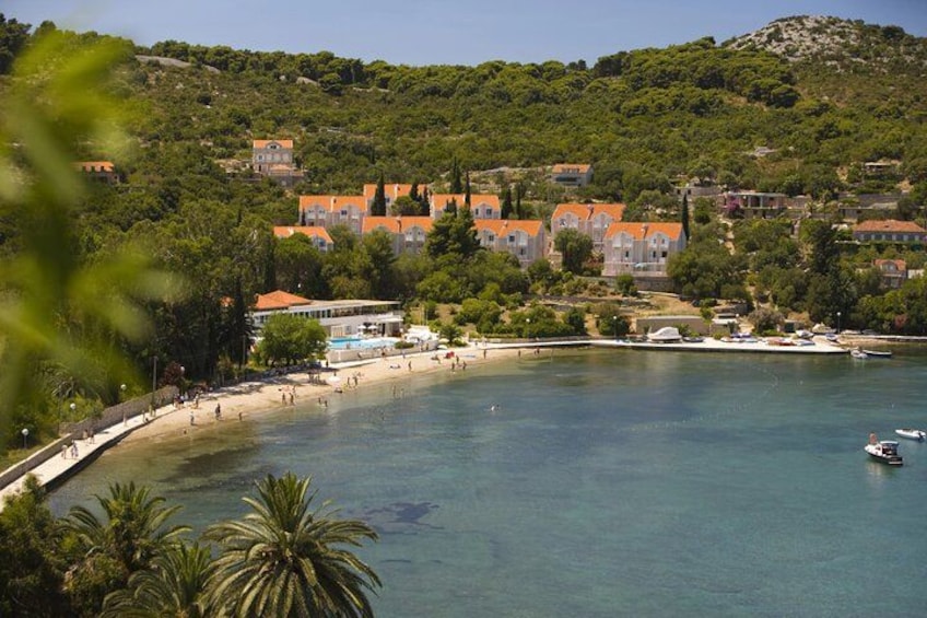 Una località balneare con spiaggia, barche ed edifici dai tetti arancioni. 3
