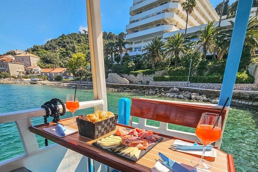 A boat with a table set with food and drinks, a view of a coastal town and water. 5