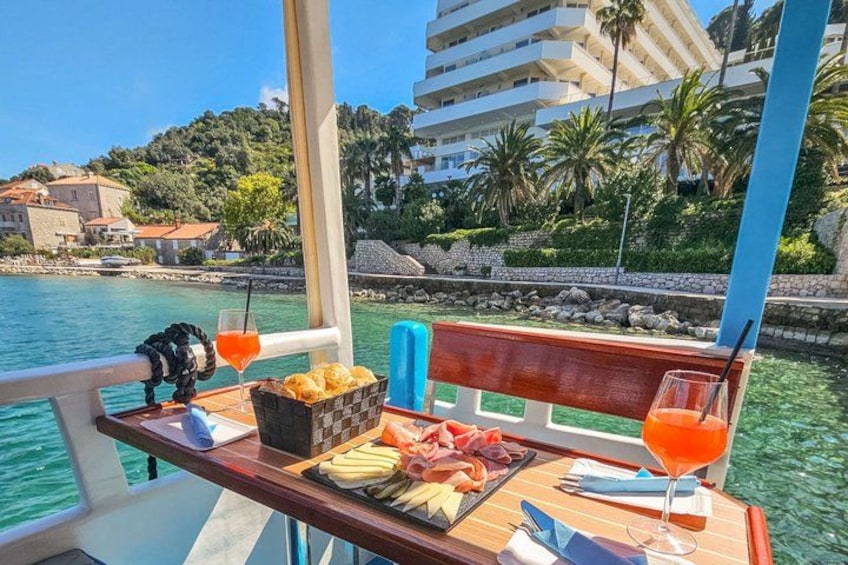 A boat with a table set with food and drinks, a view of a coastal town and water. 3