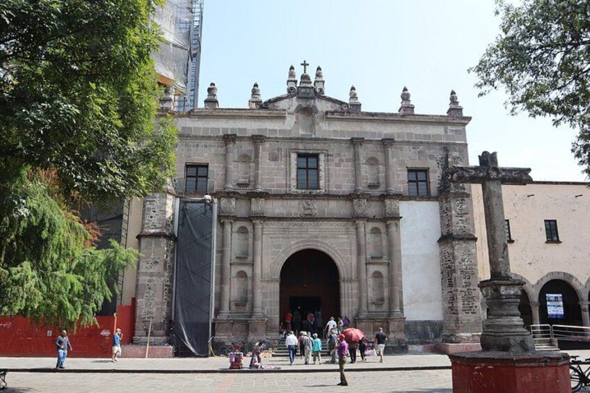 A historic building with a large archway and columns, surrounded by trees and a few people. 4
