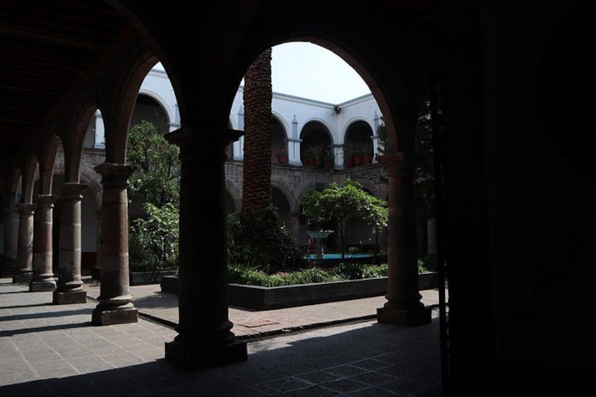 An architectural structure with arches, a courtyard, and a building in the background. 5