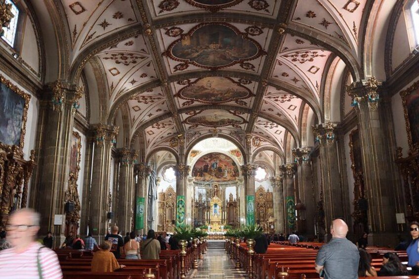 An ornate church interior with high ceilings, detailed frescoes, and rows of pews. 2