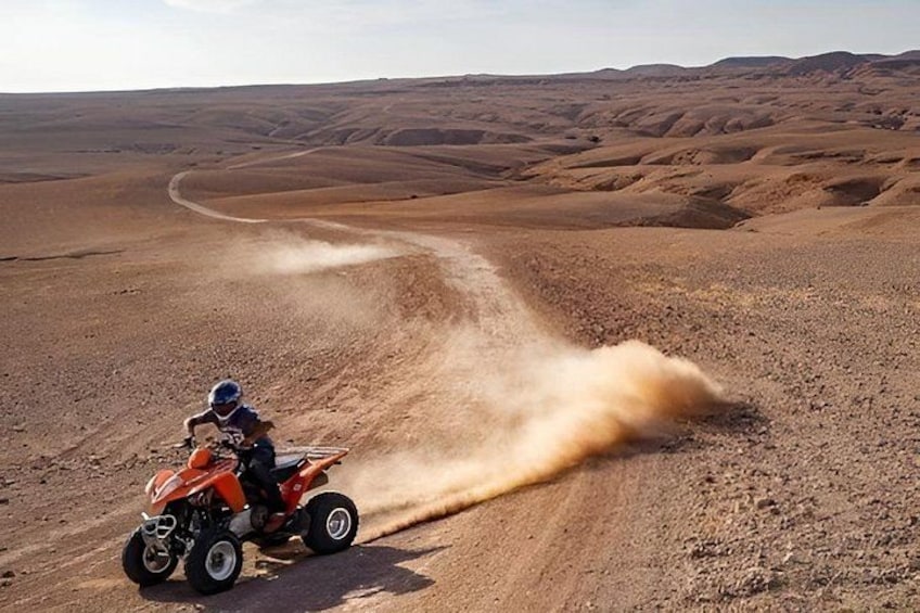 A person riding a quad bike on a dirt path in a desert landscape. 3