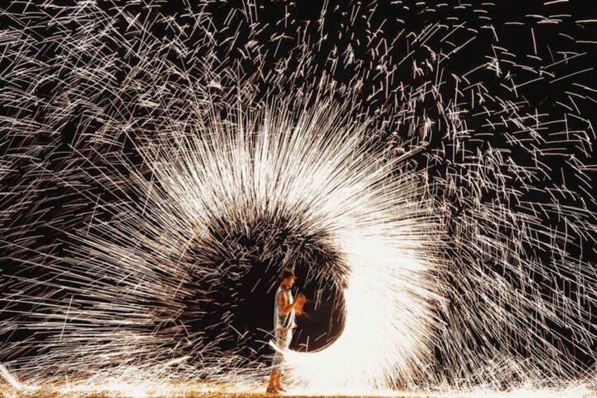 A person standing in front of a large, bright light source with sparks flying outward. 2