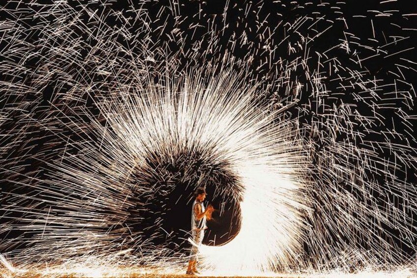 A person standing in front of a large, bright light source with sparks flying around. 2