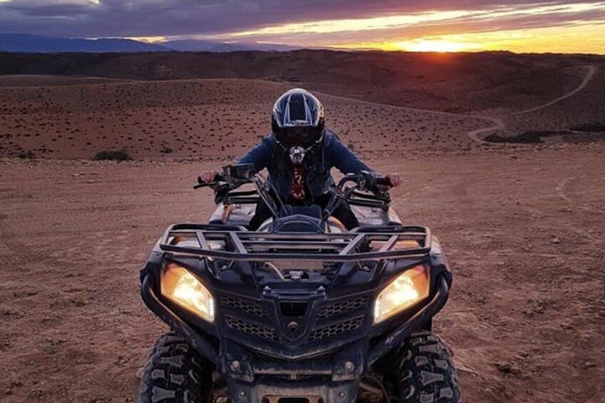 A person riding an ATV in a desert landscape during sunset. 4