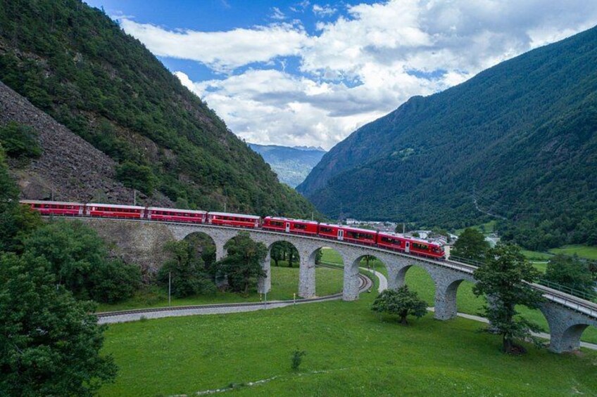 A red train crossing a stone bridge over a valley. 2