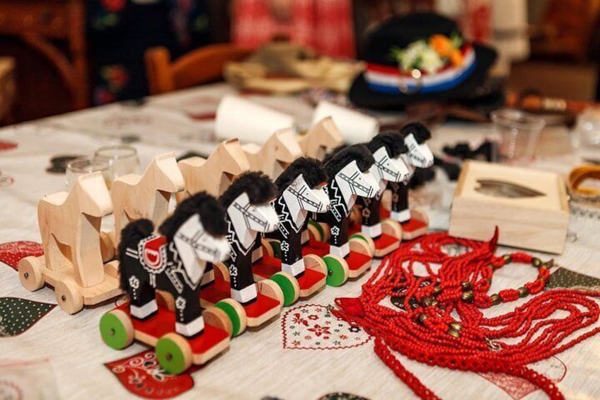 Trenes de juguete de madera, collares de cuentas rojas y una mesa con mantel a cuadros. 1