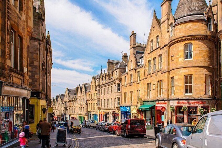A historic street lined with traditional buildings, a clear sky, and parked cars. 4