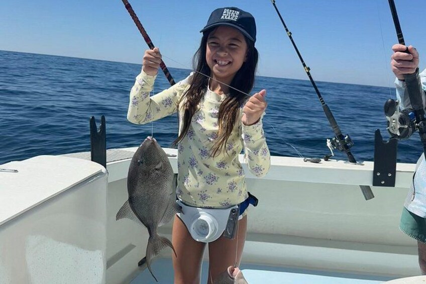 A person holding a fish on a boat, with the ocean in the background. 5