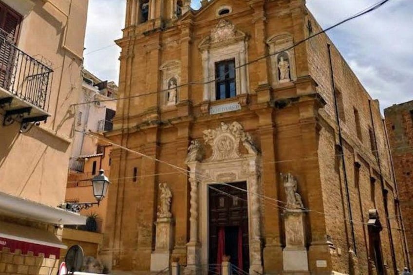 Un edificio histórico con detalles arquitectónicos ornamentales, una entrada destacada y una puerta roja. 2