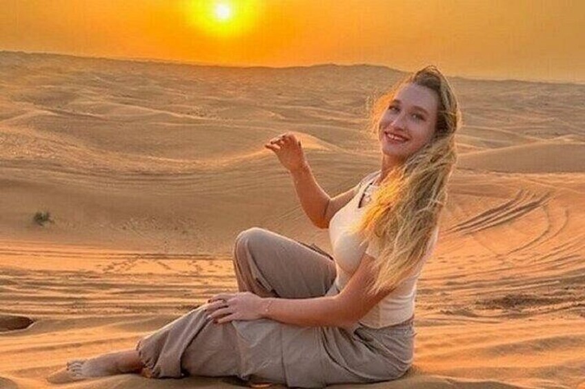 A person sitting on sand dunes during sunset. 4