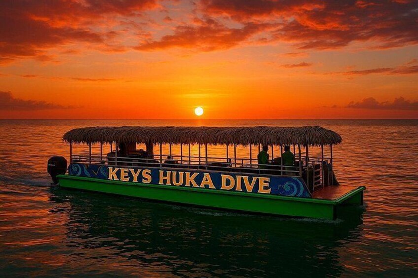 Un barco llamado 'KEYS HUKA DIVE' en aguas tranquilas durante el atardecer. 1