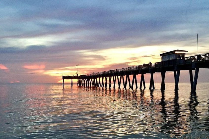 A pier extending into calm water with a sunset in the background. 2
