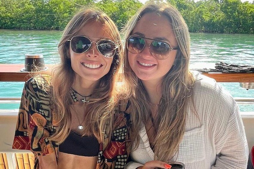 Dos personas en un bote, con agua y vegetación al fondo. 2