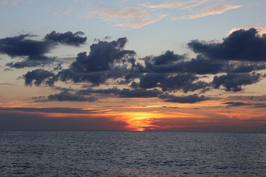 A sunset over a body of water with clouds in the sky. 3