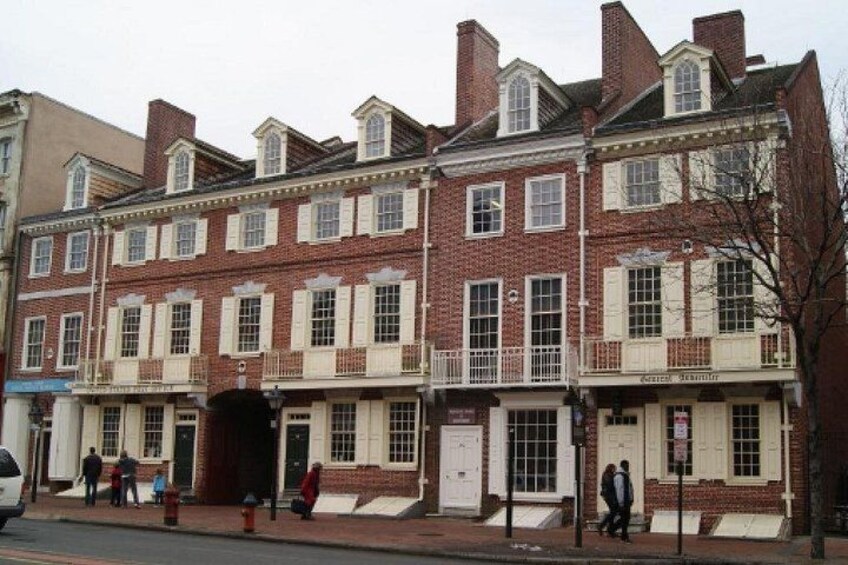 A row of red brick buildings with white trim and multiple windows. 1