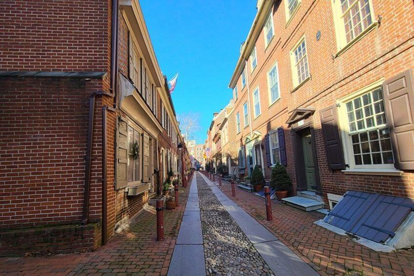 A brick street lined with buildings, a clear blue sky, and a gravel path. 2