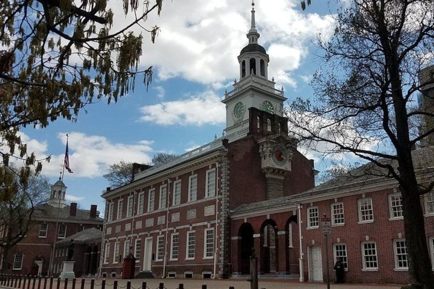 A large brick building with a clock tower, surrounded by trees and a clear sky. 2
