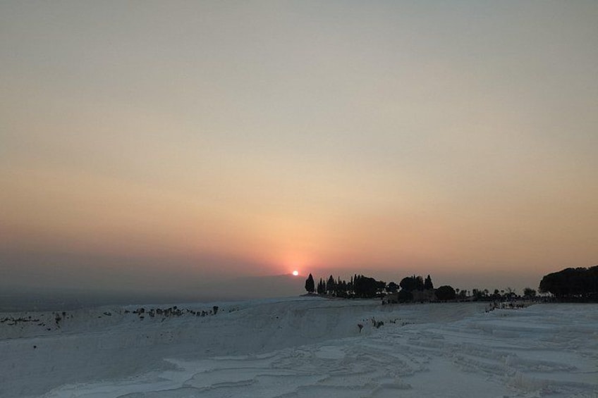 Atardecer sobre un paisaje nevado con siluetas de árboles y edificios. 4