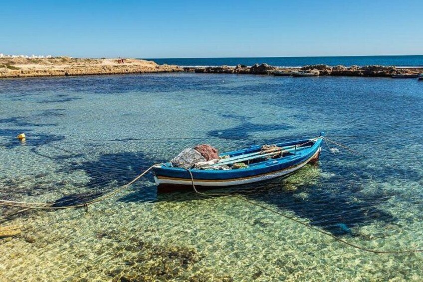 A small blue boat tied to a rocky shore with clear water. 4