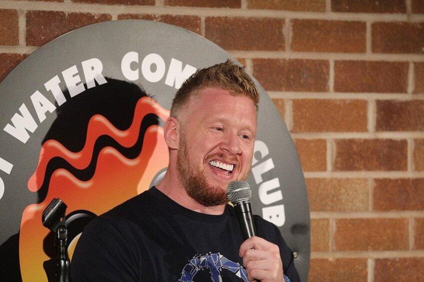A person holding a microphone in front of a backdrop with a logo that includes the text 'WATER CLUB'. 2