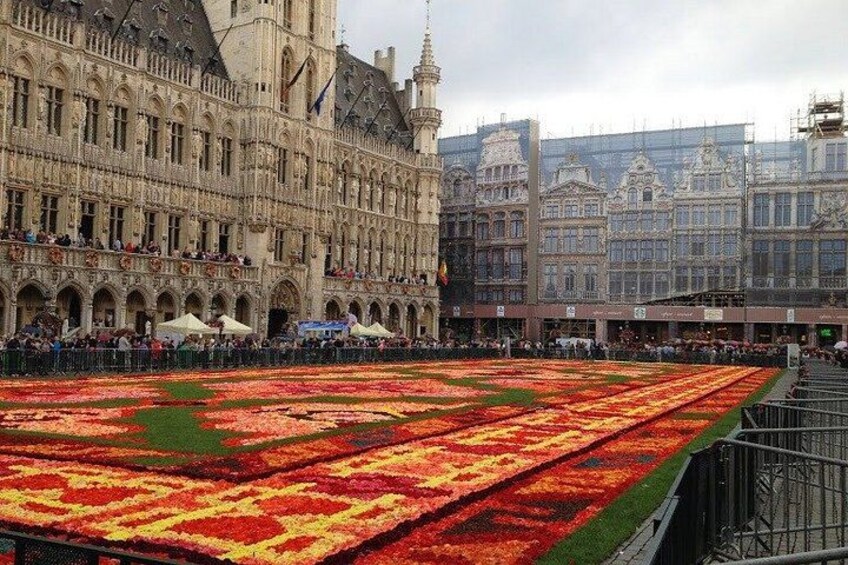 A large flower display in front of a historic building with multiple arches and a tall tower. 2
