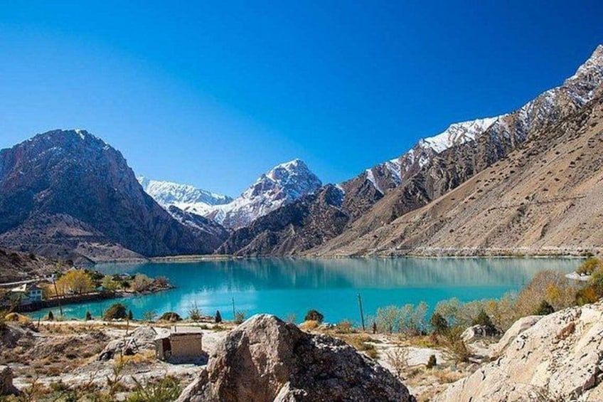 Un lago de montaña con picos nevados, cielo azul despejado y terreno rocoso. 5