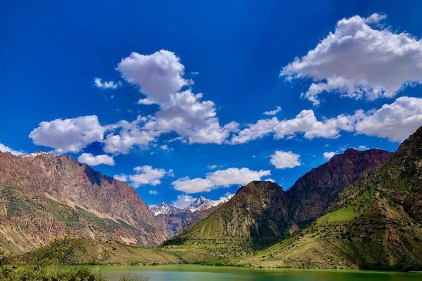 Un paisaje montañoso con un lago y un cielo azul despejado con nubes. 4