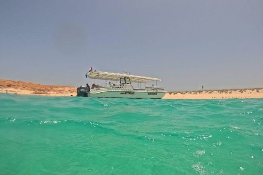 A boat on turquoise water near a sandy beach. 5