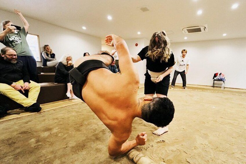 A person performing a handstand in a room with an audience. 4