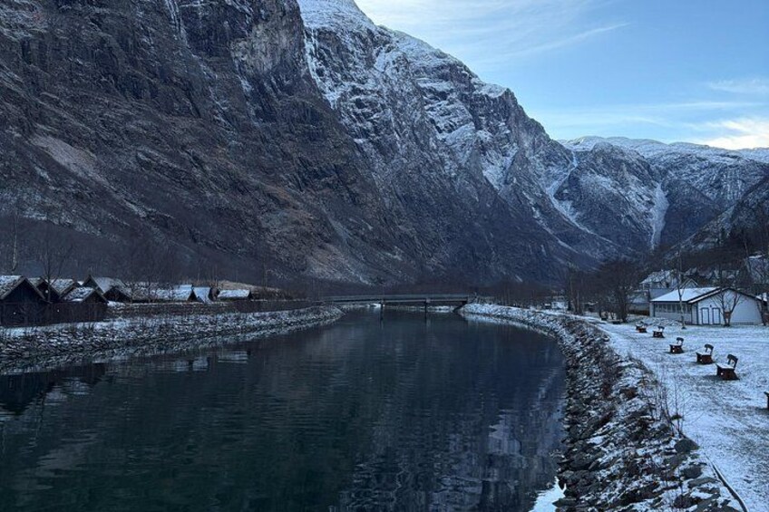 A snow-covered landscape with a river, mountains, and small buildings. 3