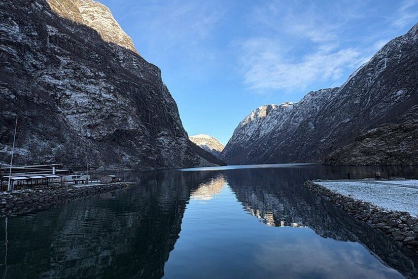 A calm lake surrounded by steep, rocky mountains with clear reflections. 2