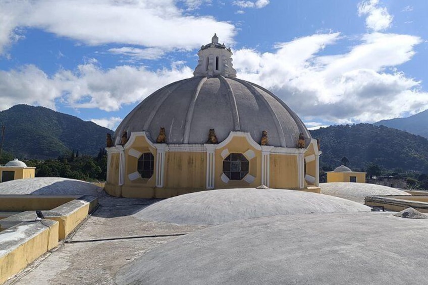 Un edificio de gran tamaño con forma de cúpula y estatuas en su fachada, con montañas al fondo. 5