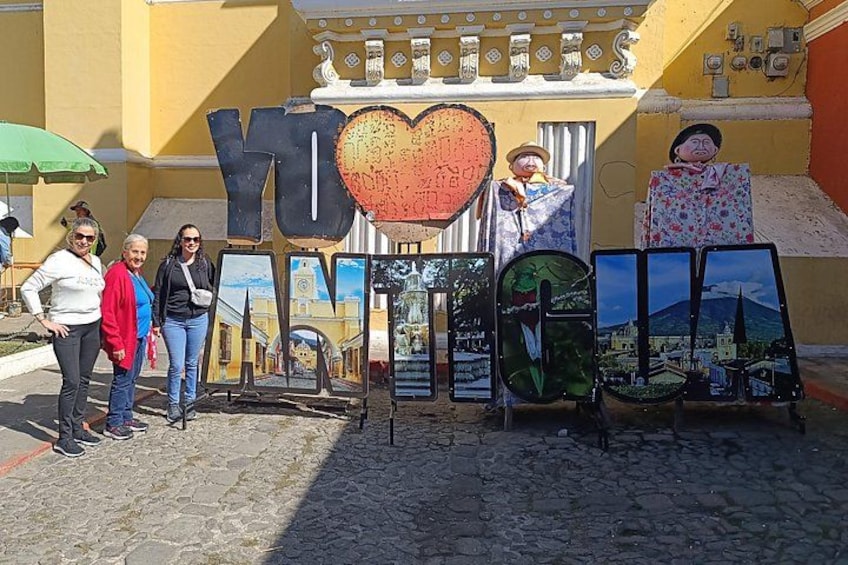Et vejskilt med store bogstaver 'YO' og 'LOVE', et hjerte-symbol og flere indrammede billeder af landskaber. 3
