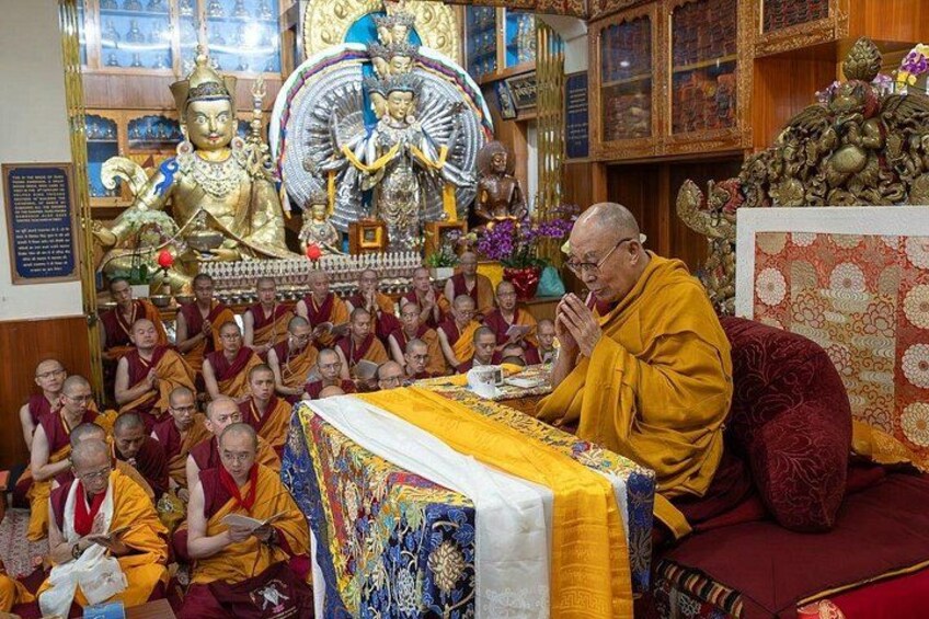 A group of monks in a temple, with a large statue and ornate decorations in the background. 4