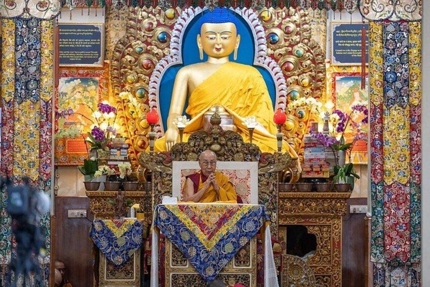 A richly decorated shrine with a large statue of a seated figure, intricate patterns, and various religious artifacts. 1
