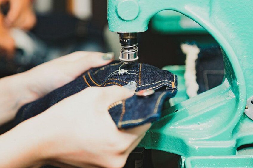 A person using a sewing machine to stitch denim fabric. 1