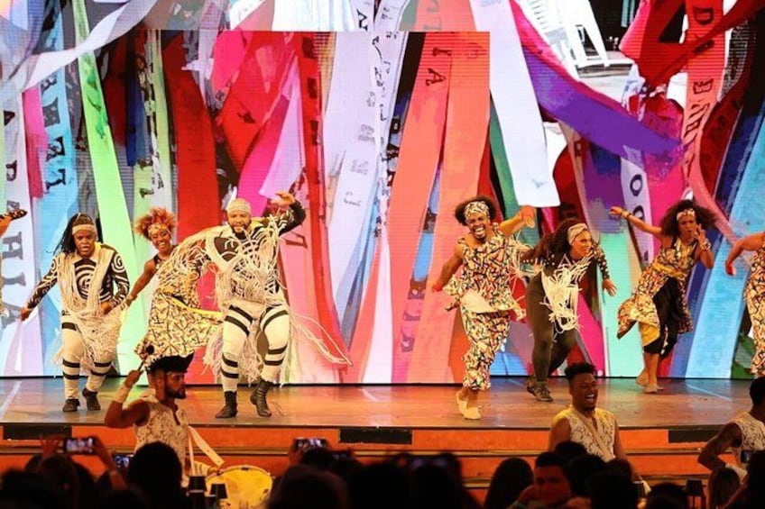 A group of dancers performing on a stage with colorful drapes in the background. 5